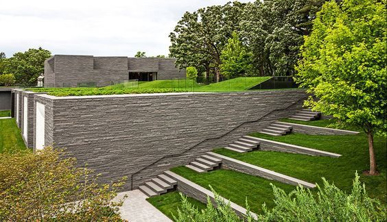 a house with grass on the roof and stairs leading up to it's second floor