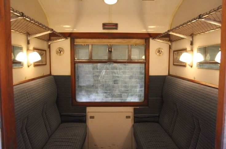 the inside of a small train car with two benches and mirrors on the side wall