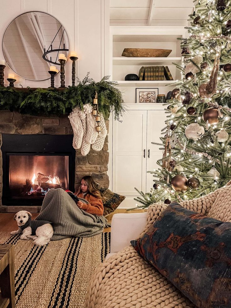 a woman laying on the floor next to a christmas tree in front of a fireplace