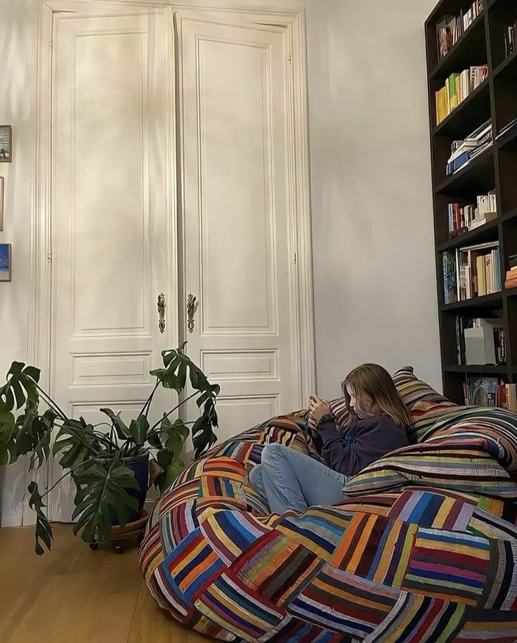 a woman sitting on a bean bag chair in a living room with bookshelves