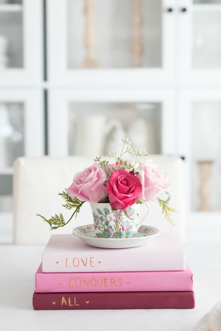 pink roses in a teacup on top of two books