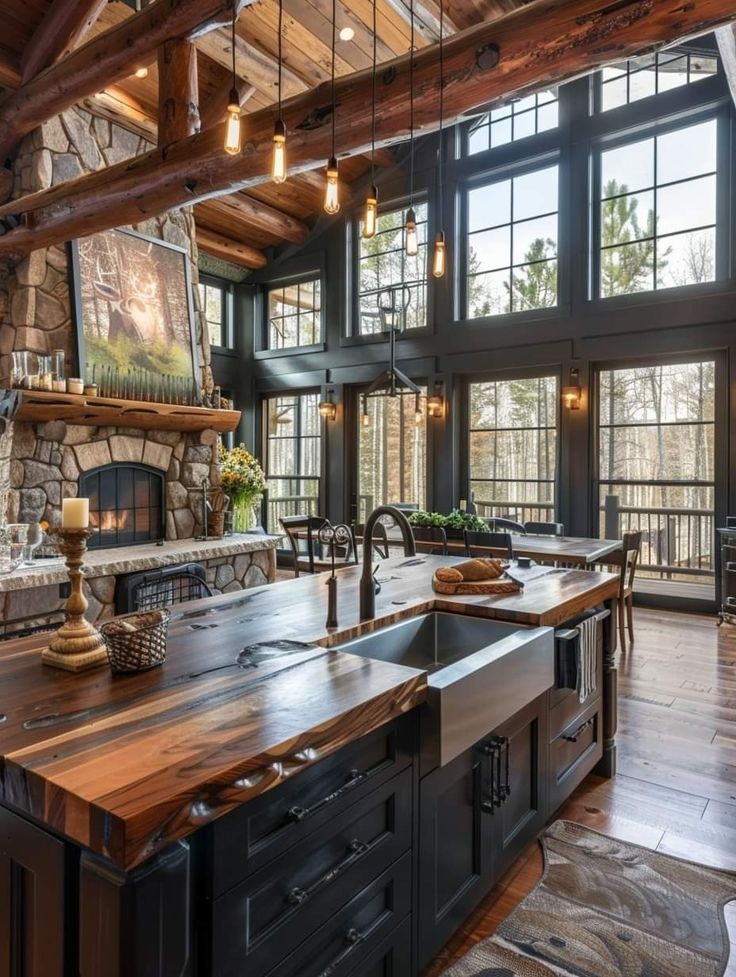 a large kitchen with an island in front of a fireplace and lots of windows on the wall