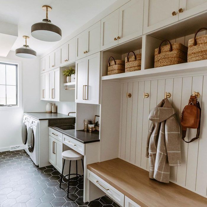 a laundry room with white cabinets and black counter tops is pictured in this image, there are baskets on the shelves above the washer