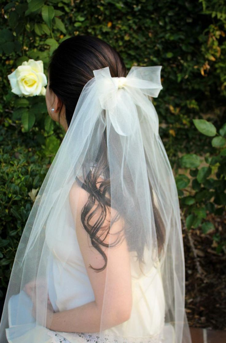 a woman wearing a veil and sitting on a bench with a flower in her hair