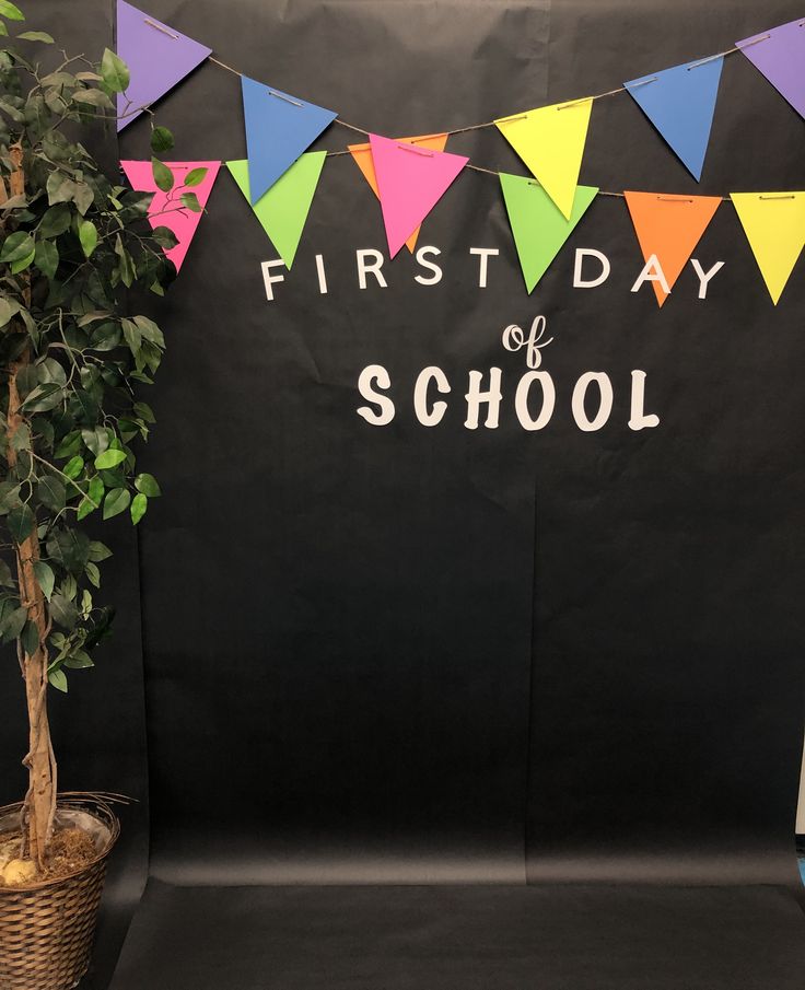 the first day of school sign next to a potted plant