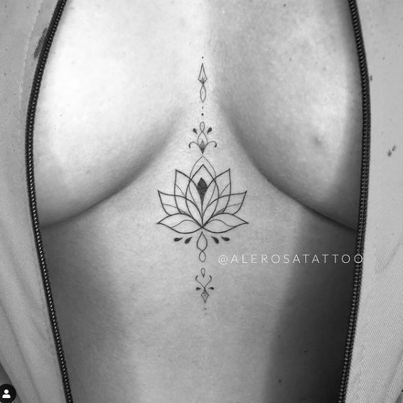 a black and white photo of a woman's breast with a lotus tattoo on it