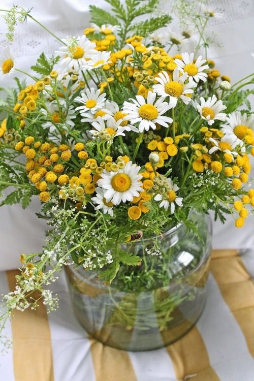 a vase filled with lots of yellow and white flowers