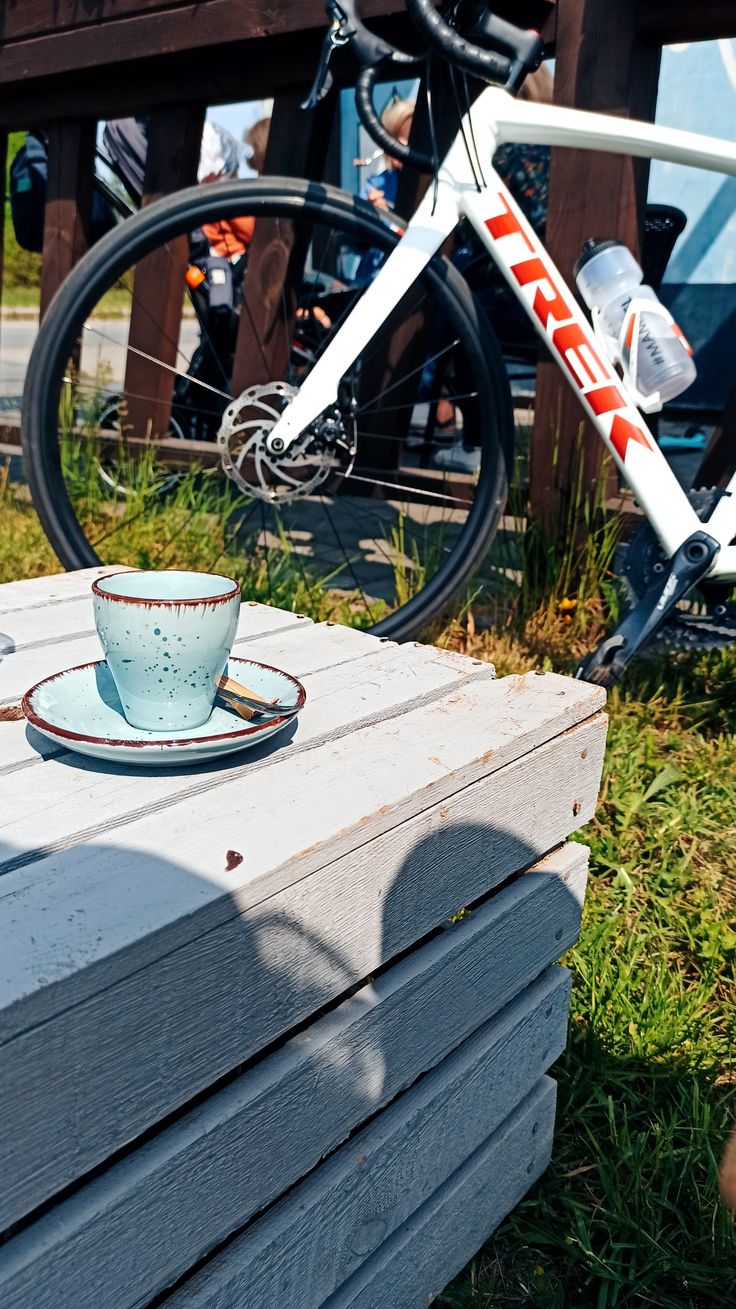 a cup and saucer sitting on top of a wooden box next to a bicycle