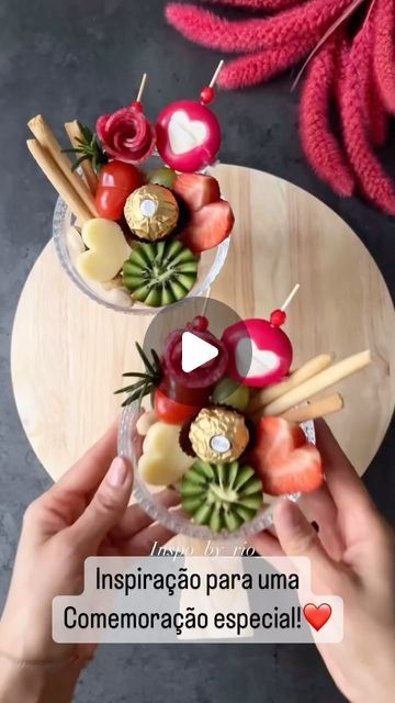 two people holding up small bowls filled with fruit and veggies on top of a table