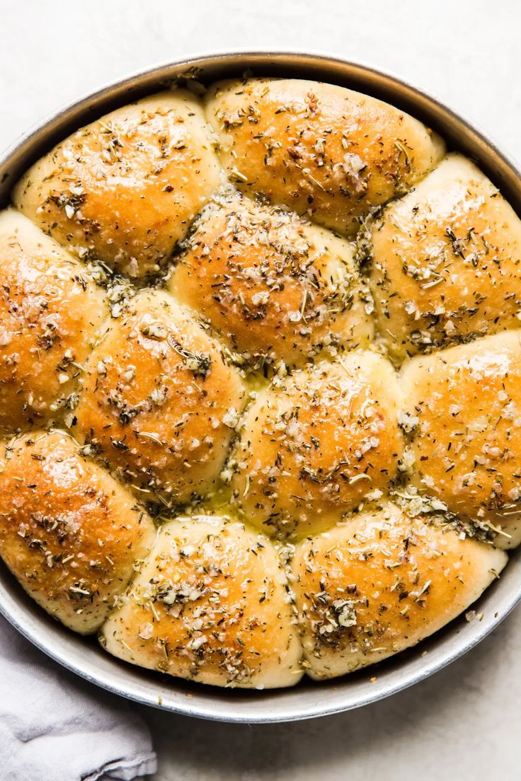 a pan filled with bread rolls covered in cheese and seasoning sprinkled on top