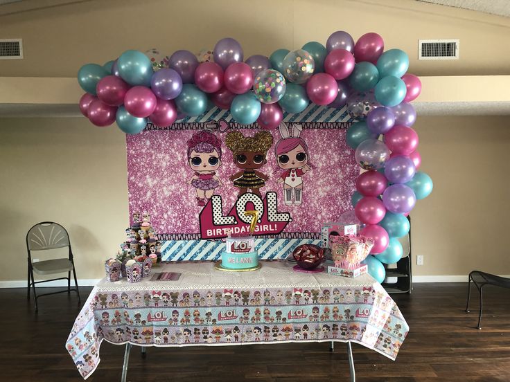 a table topped with balloons and cake next to a wall