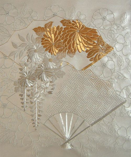 a white table cloth with gold leaf and fan design on the front, along with other decorative items