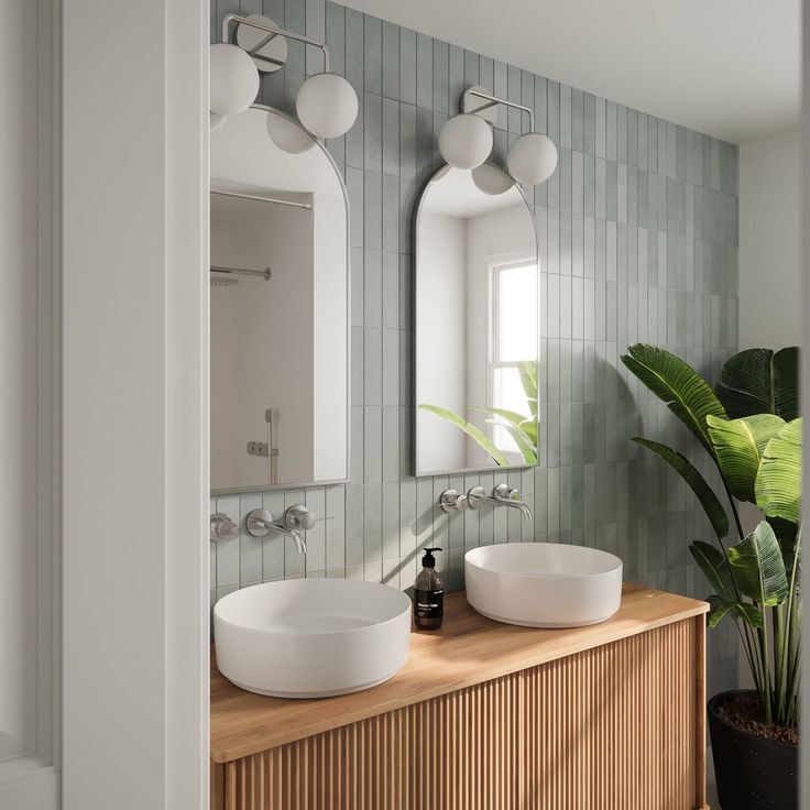 two white sinks sitting on top of a wooden counter next to a potted plant