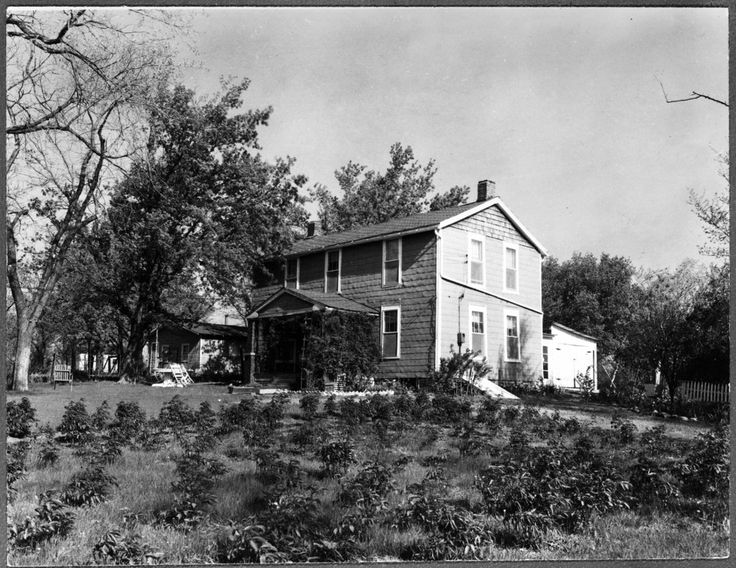 an old black and white photo of a house in the middle of some grass with trees around it