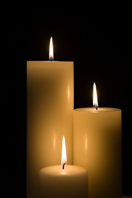 three white candles lit up in the dark