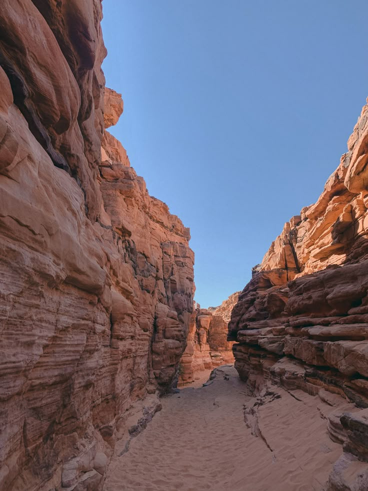 a narrow canyon in the desert with sand and rocks