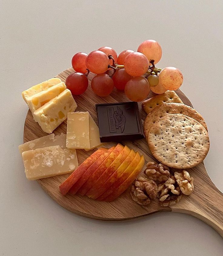 an assortment of cheeses, crackers and nuts on a wooden board