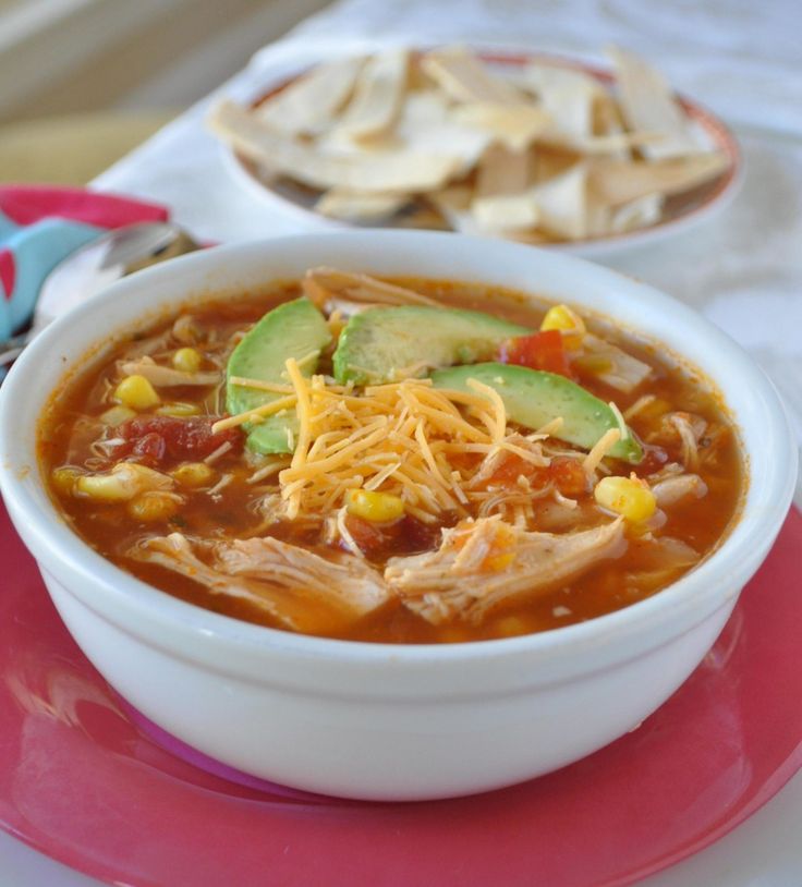 a bowl of chicken tortilla soup on a pink plate