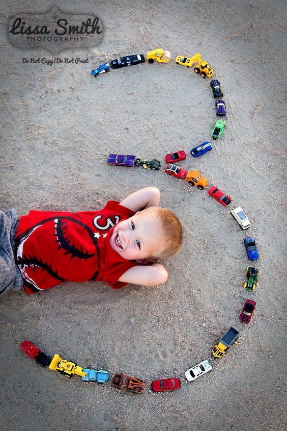 a little boy laying on the ground with his toy cars