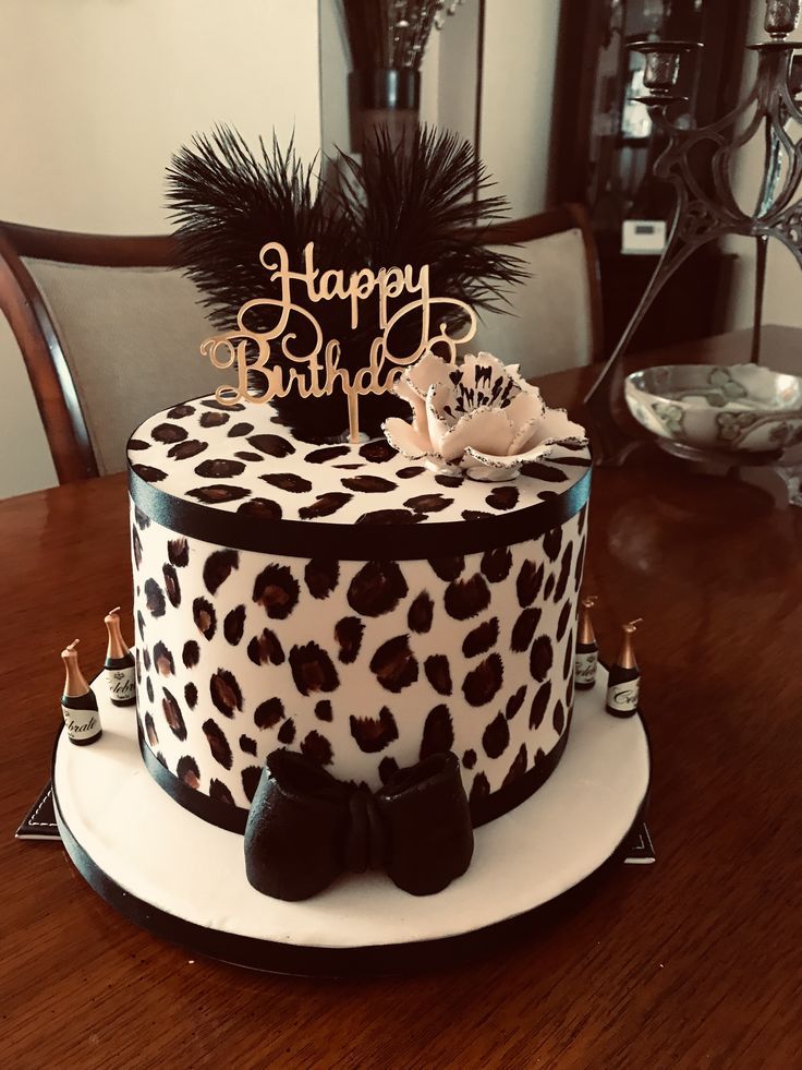 a birthday cake decorated with black and white leopard print on a wooden dining room table