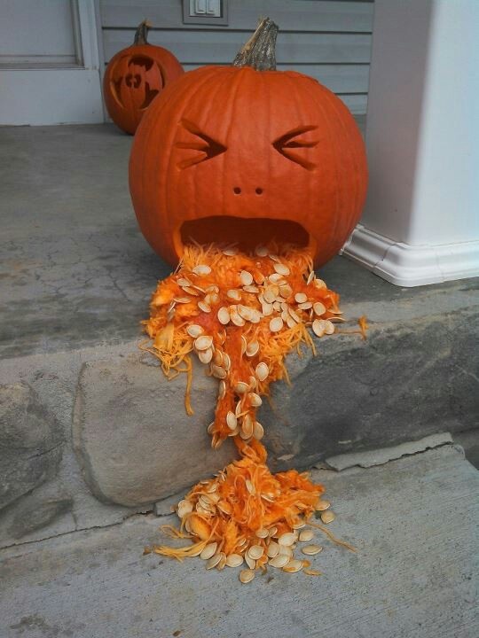 a pumpkin that has been carved into a face with nuts all over it's body