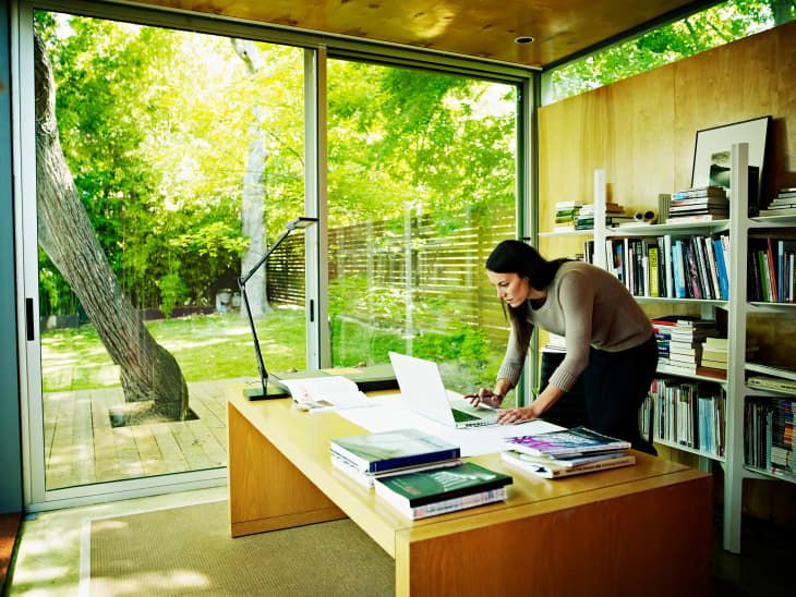 a woman standing at a desk in front of a window