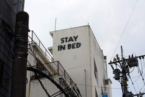 a sign that says stay in bed on the side of a building with stairs leading up to it