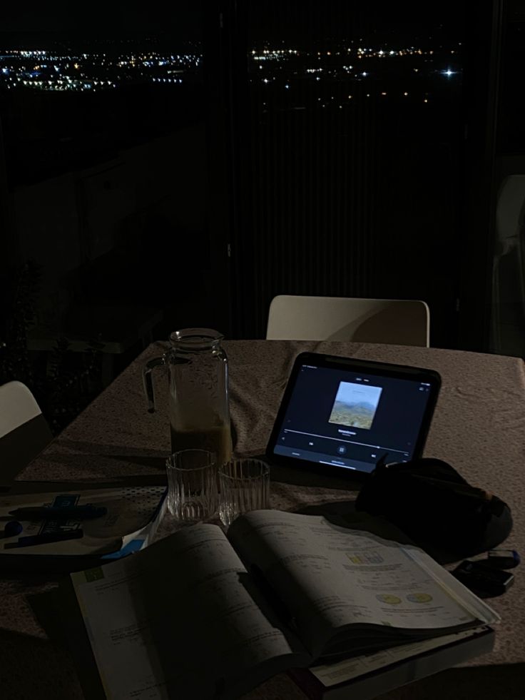 an open book sitting on top of a table next to a cup and tablet computer