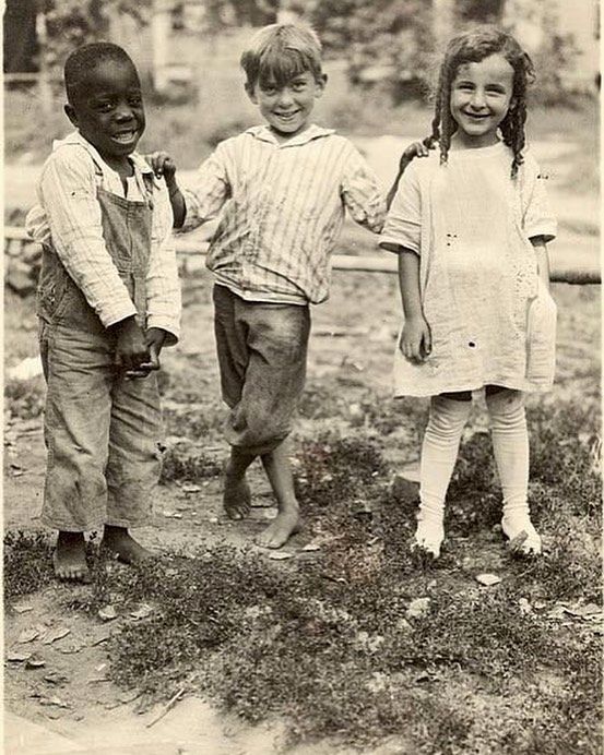 three young children are standing in the grass