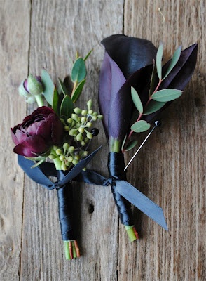 two boutions with purple flowers and green leaves on a wooden surface, one being tied to the other