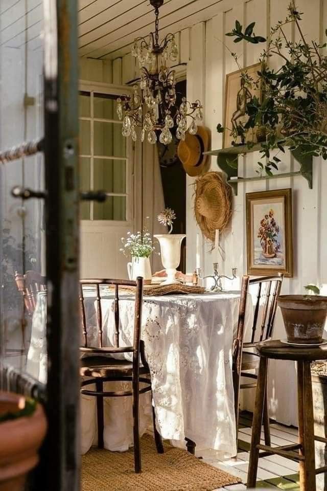 the dining room table is covered with white linens and has potted plants on it