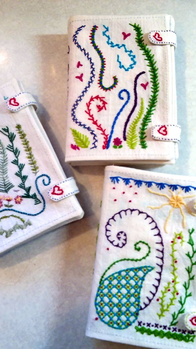 three embroidered coasters with designs on them