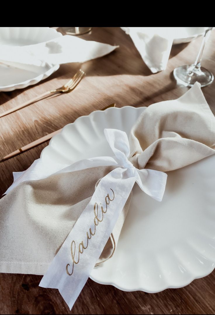 a white plate topped with a napkin on top of a wooden table next to silverware