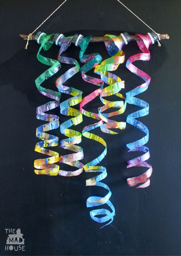 a piece of art made out of strips of colored paper hanging from a string on a wall