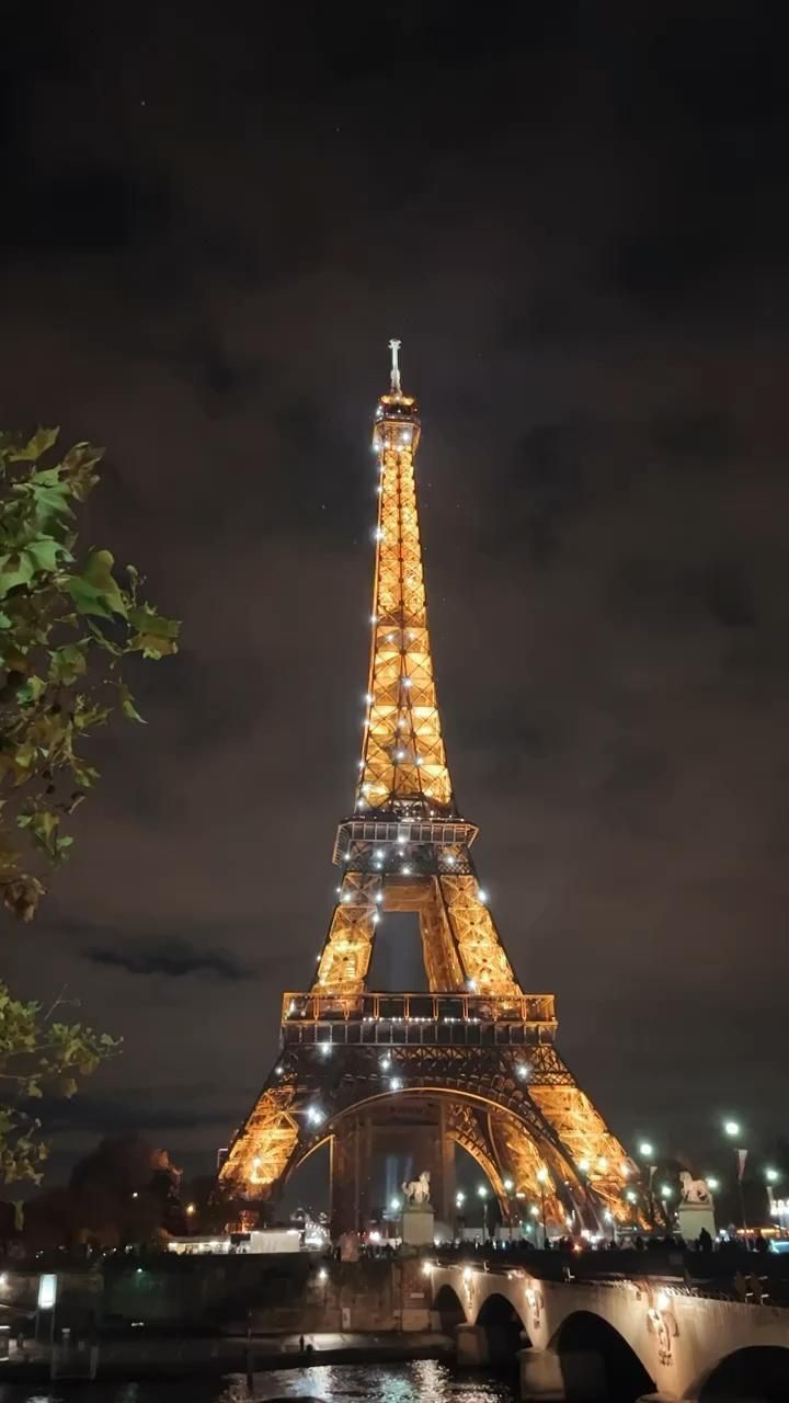 the eiffel tower lit up at night with lights on it's sides