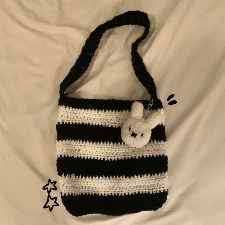 a crocheted bag with a stuffed animal in the pocket on a white sheet