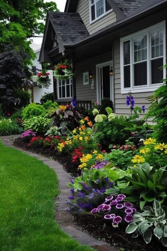 a house with lots of flowers in the front yard and walkway leading up to it