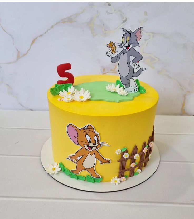 a birthday cake with an image of the mouse and cat on it's side