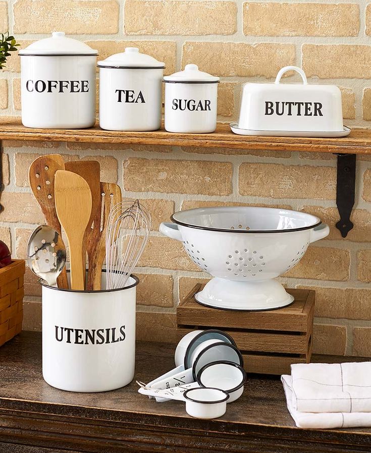 kitchen utensils are sitting on a shelf in front of a brick wall and wooden shelves