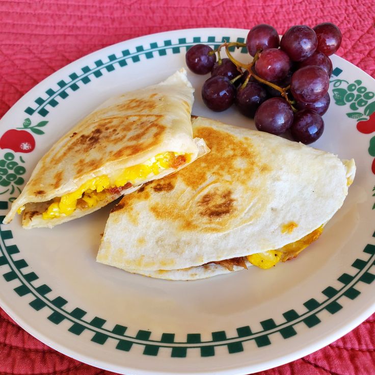 an egg and cheese quesadilla on a plate with grapes