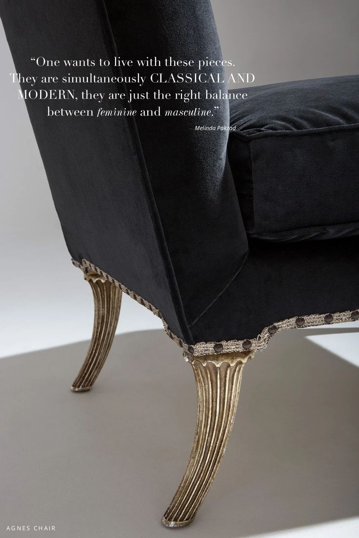 a black velvet chair with gold trimmings on the legs and back, in front of a white background