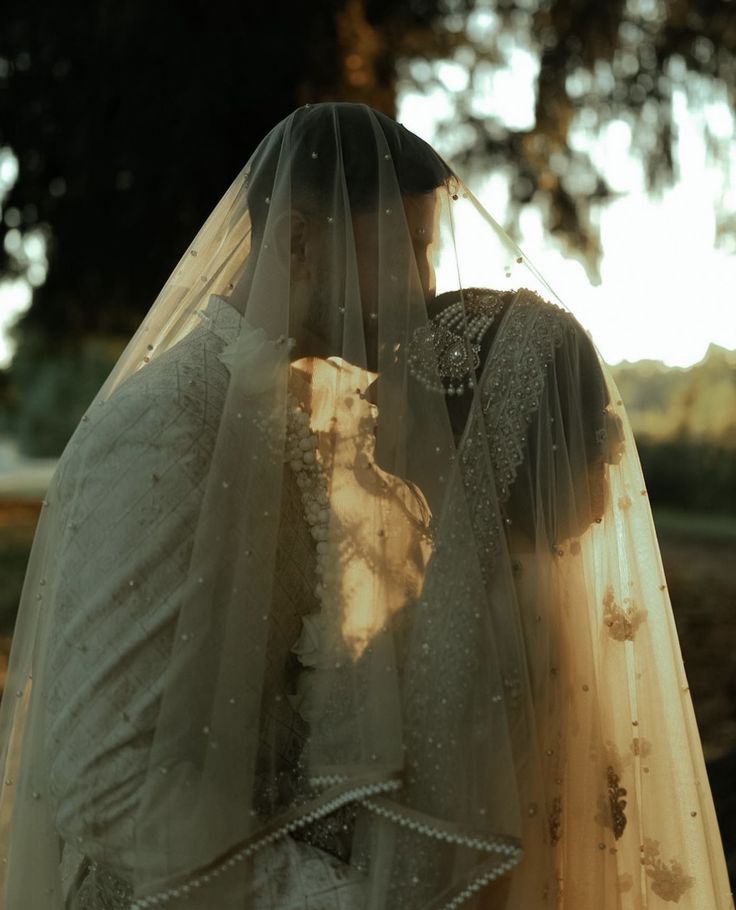 the bride and groom are kissing under their veil