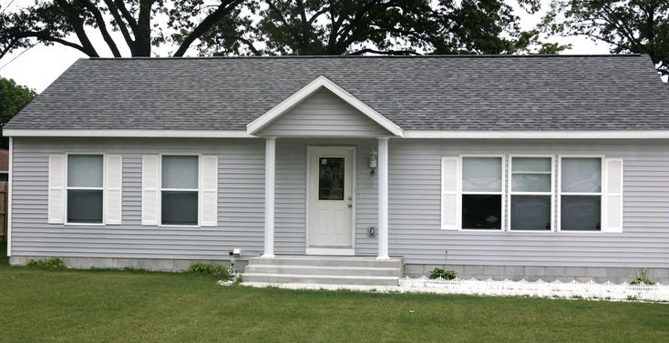 a small gray house with white trim and two windows on the front door is shown