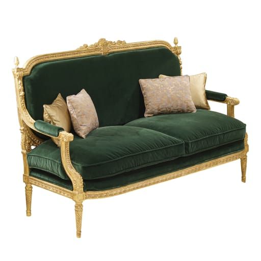 a green velvet couch with gold trimmings and decorative pillows on the armrests