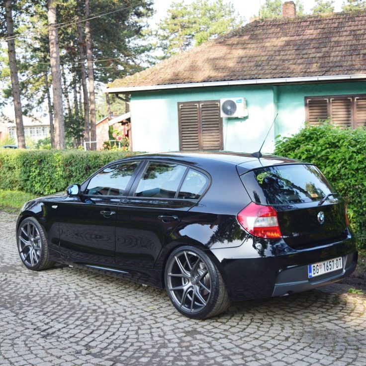 a black car parked in front of a blue house on a cobblestone road