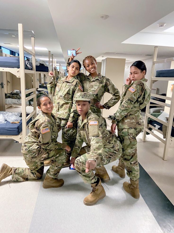 four female soldiers posing for a photo in a room with bunk beds and bunk beds