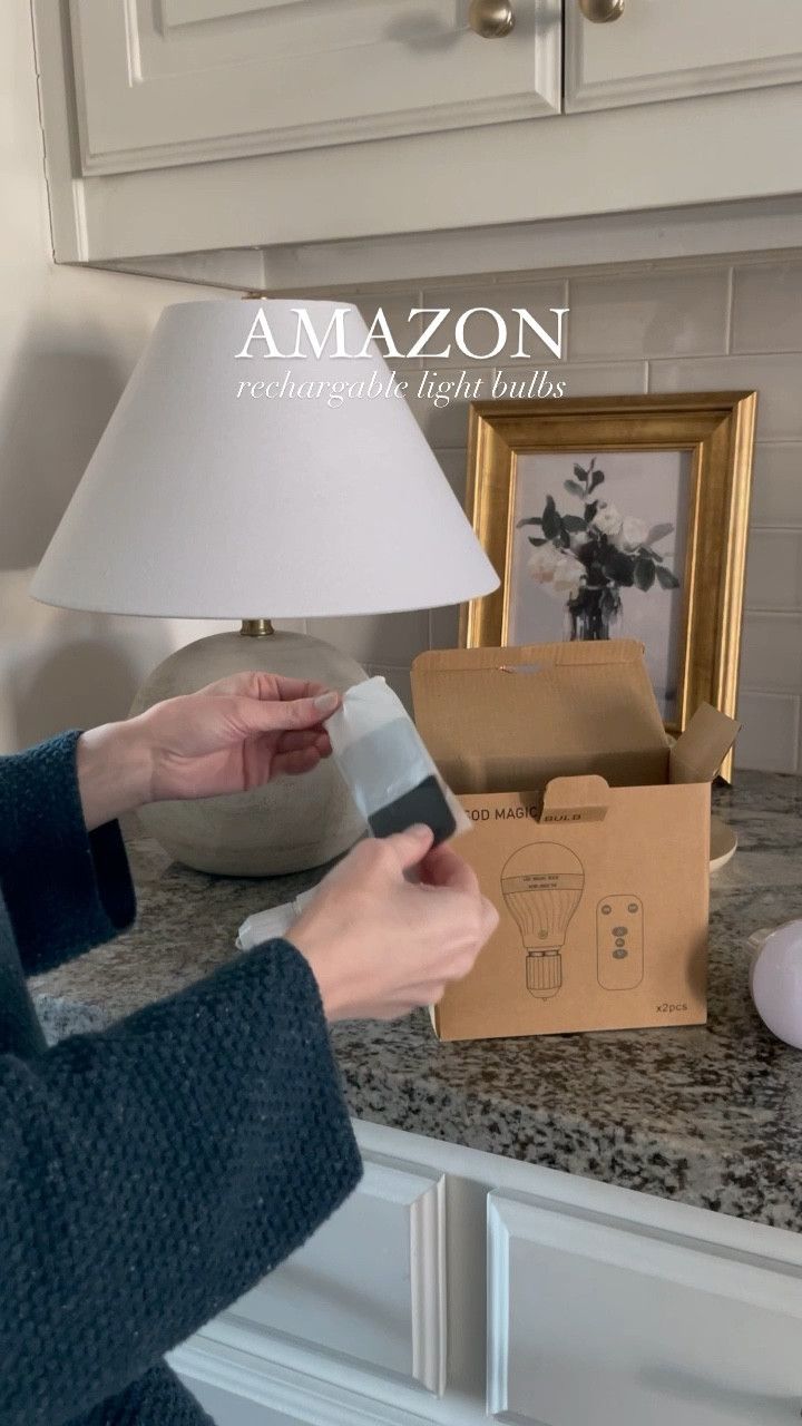 a woman is using a lamp on the counter in front of a box with an amazon logo