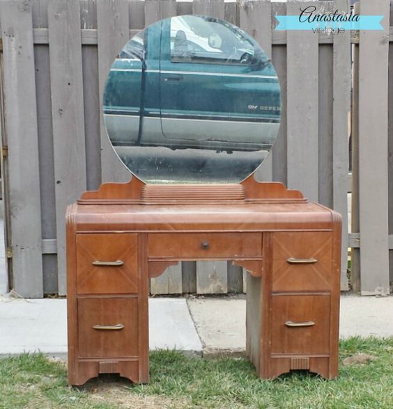 an old vanity with a mirror on it in front of a wooden fence and grass