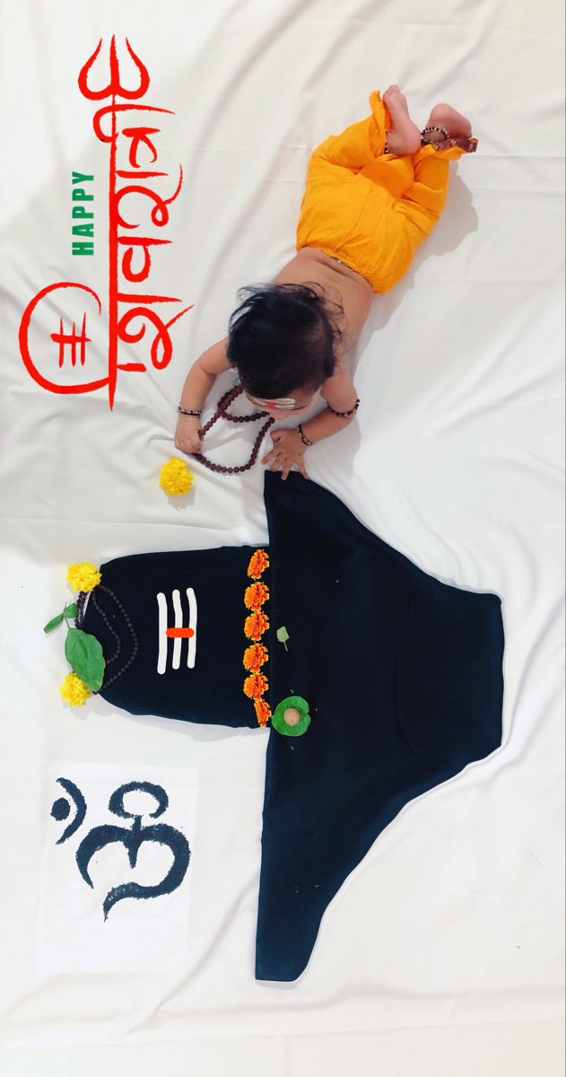 a baby laying on top of a white sheet next to numbers and an orange shirt