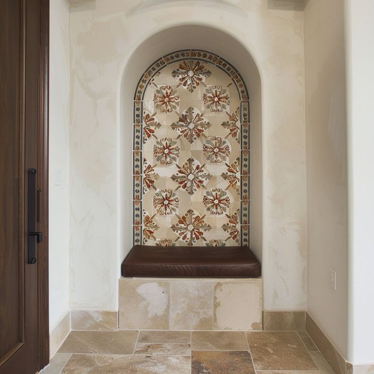 an arched window sits in the middle of a tiled wall with a bench underneath it